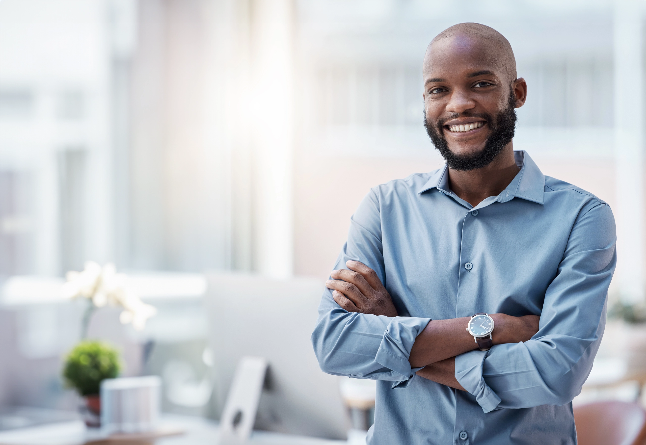 male man standing with arms crossed in front of workspace